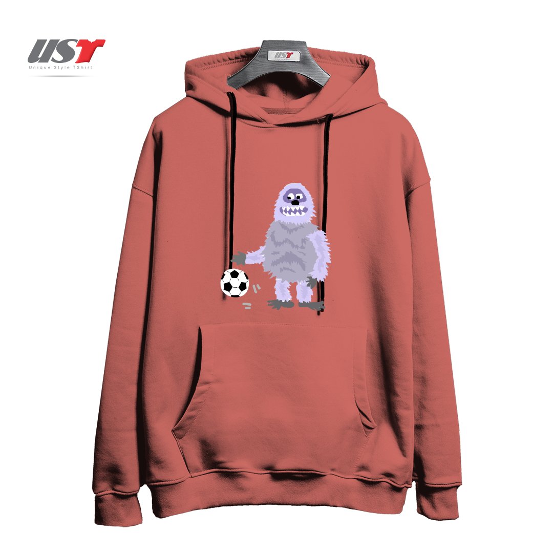 طرح FUNNY ABOMINABLE SNOWMAN PLAYING SOCCER هودی اورسایزرنگ آجری